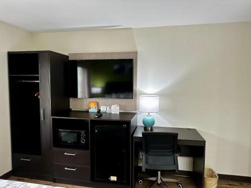 a room with a desk with a lamp and a tv at Sleep Inn Savannah Gateway I-95 in Savannah