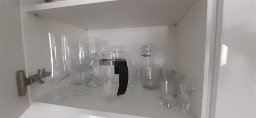 a shelf with many glass vases in a cabinet at Apartament Morze i Las in Mrzeżyno