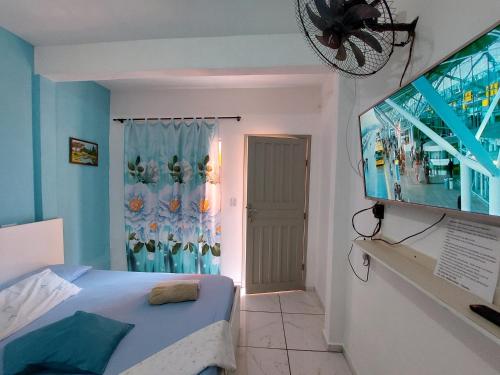 1 dormitorio con 1 cama, TV y ventana en Guest House Palmeiras, en Cabo Frío