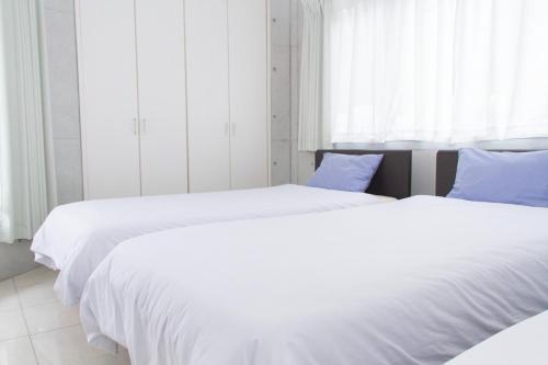 two beds in a bedroom with white sheets and blue pillows at Shiraho Villa - Vacation STAY 20487v in Shiraho