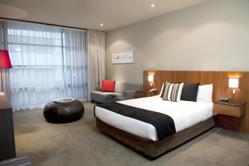 a hotel room with a large bed and a chair at Mantra Hindmarsh Square in Adelaide