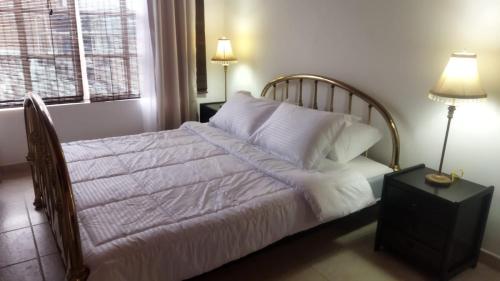 - un lit avec des draps et des oreillers blancs dans une chambre dans l'établissement Casa Vacacional cerca al Parque del Café, à Montenegro