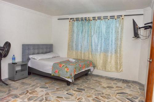 Schlafzimmer mit einem Bett und einem Fenster in der Unterkunft Apartahotel Romor in Cali