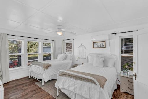 2 camas en un dormitorio con paredes y ventanas blancas en The Ouachita Depot en Mena