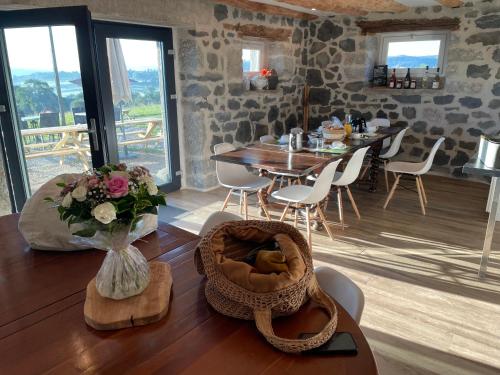 a dining room with a table and chairs and a vase with flowers at Le Buron du Bessou in Saint-Urcize