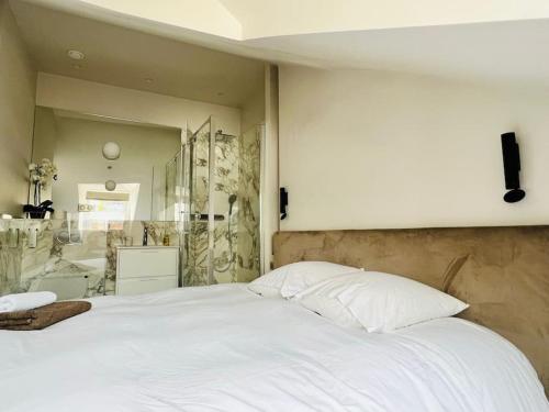 une chambre avec un grand lit blanc et une salle de bain dans l'établissement Le StayParis - Charmant logement au cœur du Marais, à Paris