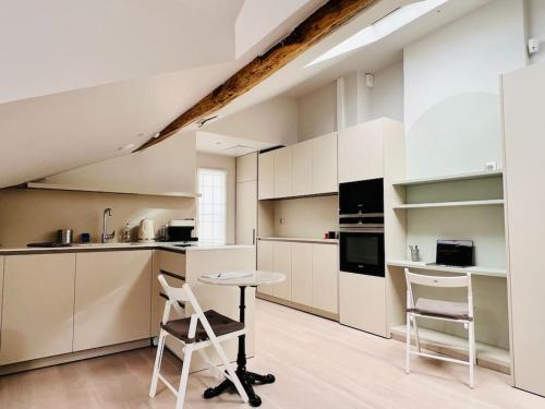 une cuisine avec des armoires blanches et une table et des chaises dans l'établissement Le StayParis - Charmant logement au cœur du Marais, à Paris