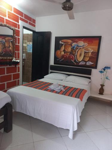 1 dormitorio con 1 cama con una pintura en la pared en Hotel Mi Remanso, en Arboletes