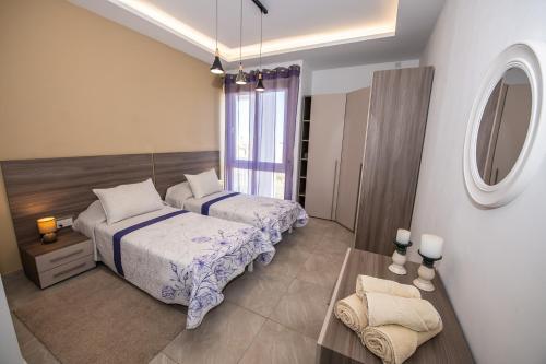 a bedroom with two beds and a table and a mirror at Clifftop Modern Apartment in Mellieħa