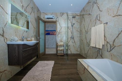 a bathroom with a sink and a bath tub at Clifftop Modern Apartment in Mellieħa