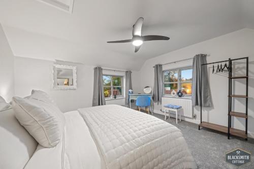 1 dormitorio blanco con 1 cama y ventilador de techo en Luxury cottage, 13 guests with 2 hot tubs in Hoar Cross, Staffs, en Newborough
