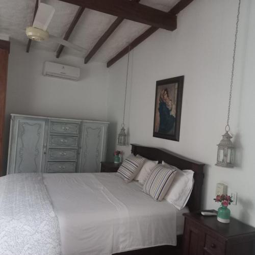 a bedroom with a white bed and a painting on the wall at casa lumka hotel boutique spa in Mariquita