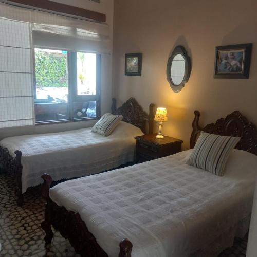 two beds in a room with a window at casa lumka hotel boutique spa in Mariquita