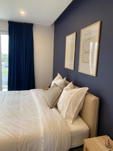 a bedroom with a white bed with a blue wall at Maison spacieuse au calme proche Colmar avec piscine in Niederentzen