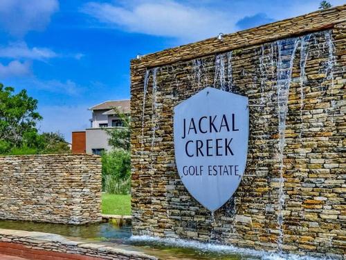a sign on a brick wall with a water fountain at 1 Bed Apartment @ Jackal Creek Golf Estate in Roodepoort