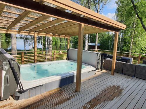a hot tub on a deck with a pergola at Villa Siirtola in Koro