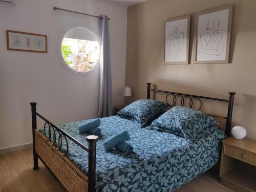 1 dormitorio con cama con sábanas azules y ventana en La Terrasse en Le Carbet