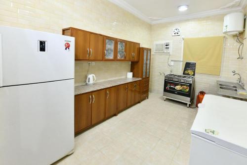 a kitchen with a white refrigerator and a stove at شاليه ليالي in AlUla