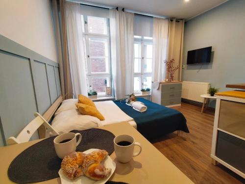 Cette chambre comprend un lit et une table avec de la nourriture. dans l'établissement Długa by Little Heaven, à Gdańsk