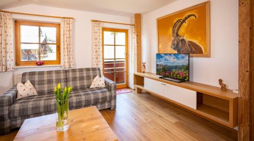 a living room with a couch and a tv at Haus Berg & Tal in Hirschegg