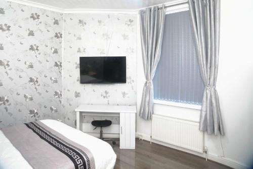 a bedroom with a bed and a desk and a television at CHEADLE HOUSE HOLIDAYS in Manchester