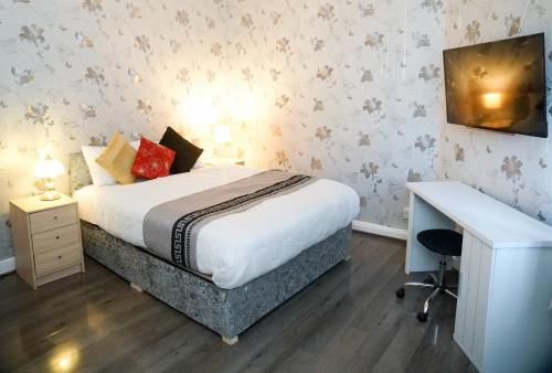 a bedroom with a bed and a desk in it at CHEADLE HOUSE HOLIDAYS in Manchester
