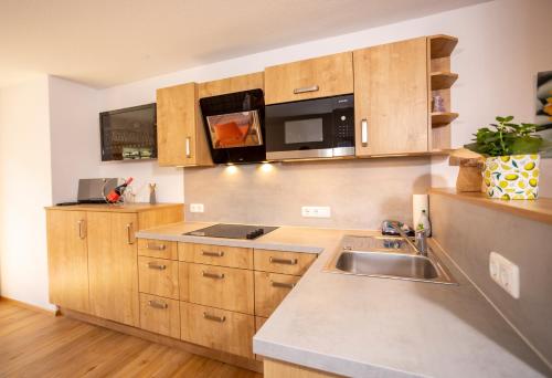 a kitchen with wooden cabinets and a sink at Haus Berg & Tal in Hirschegg