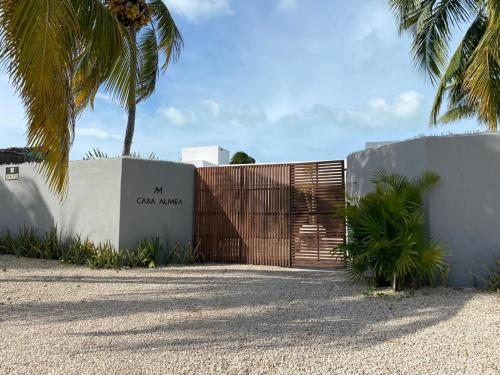 a fence with a wooden gate and a palm tree at Casa Almea Sisal in Sisal