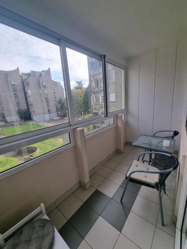 a room with a chair and a table and windows at Hawaii- 2 bdr, Arena, Sava centar, FREE PARKING in Novi Beograd