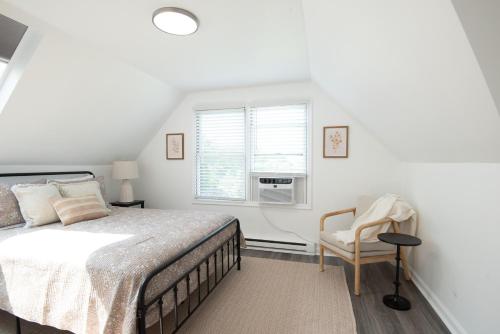 ein Schlafzimmer mit einem Bett, einem Stuhl und einem Fenster in der Unterkunft The Wren's Nest in Birdsboro