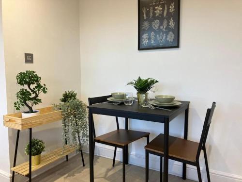 uma mesa preta e cadeiras com plantas em Awesome Refurbished 1 Bed Flat few steps to High St ! - 2 East House em Epsom