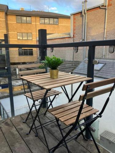 a wooden table and chairs on a balcony at Awesome Refurbished 1 Bed Flat few steps to High St ! - 2 East House in Epsom