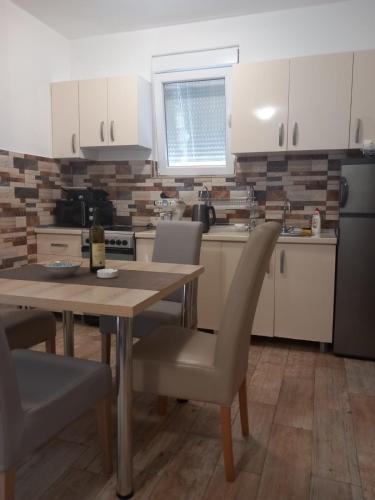 a kitchen with a wooden table with chairs and a tableasteryasteryasteryasteryastery at Apartman Gačić in Igalo