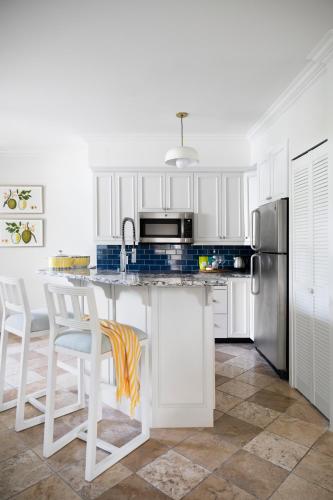 a kitchen with white cabinets and a kitchen island with stools at Point Grace in Grace Bay