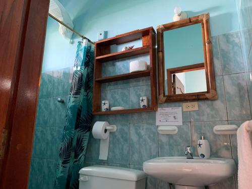 uma casa de banho com um WC, um lavatório e um espelho. em Casa Verde Vacation Garden Home em San Cristóbal