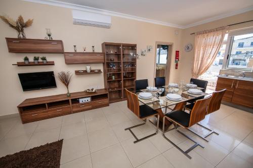 une salle à manger avec une table, des chaises et une télévision dans l'établissement Francis Flats Modern Penthouse, à Mellieħa