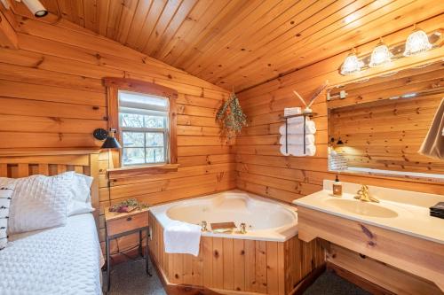 a log cabin bathroom with a tub and a sink at Arrowhead Cabin/Fields of Home in Millersburg