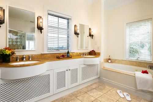 a bathroom with two sinks and a tub and a mirror at Point Grace in Grace Bay