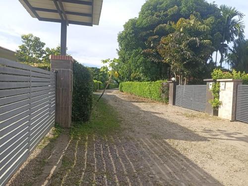 a fence and a dirt road next to a driveway at Quinta la Rivera Villavicencio in Villavicencio