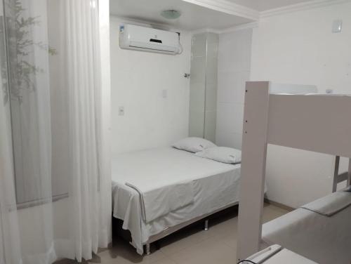a small white bedroom with a bed and a window at Hotel Vitoria Iracema in Juazeiro do Norte