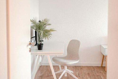 a white desk with a chair and a plant at Apartment mit Küche, Arbeitsplatz und XXL Sofa in Neuss