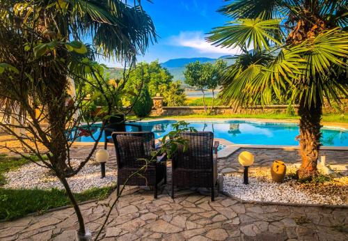 - une piscine avec 2 chaises et un palmier dans l'établissement Vila Exotic, à Kavadartsi