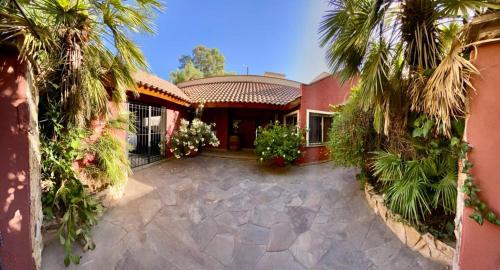 a red house with palm trees in front of it at La casita en el parque in Chacras de Coria