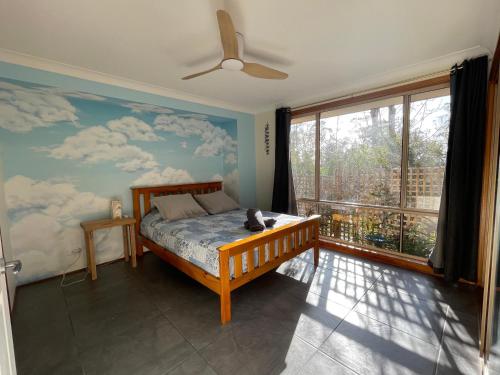 a bedroom with a bed and a large window at Family home, close to beach and town in Moruya Heads