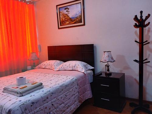 1 dormitorio con 1 cama y mesita de noche con lámpara en Tambo Huascar, en Lima