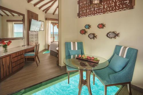 soggiorno e sala da pranzo con tavolo e sedie di Palafitos Overwater Bungalows Catamarán, Cenote & More Inclusive a Playa del Carmen