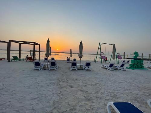 a group of chairs and swings on the beach at Modern 1 Bedroom Apartment Yas island with private beach in Abu Dhabi