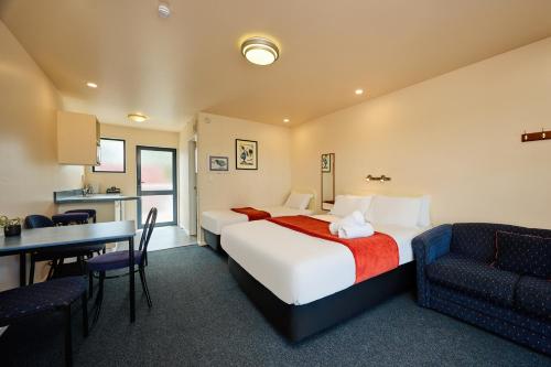 a hotel room with a large bed and a table at Mediterranean Motel Kaikoura in Kaikoura