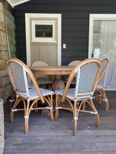 a wooden table and chairs on a porch at Avalon Beach Cottage- The Islander in Avalon