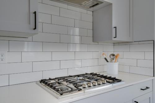 a white kitchen with a stove top and white cabinets at Modern Downtown Provo Townhome with Balcony! in Provo